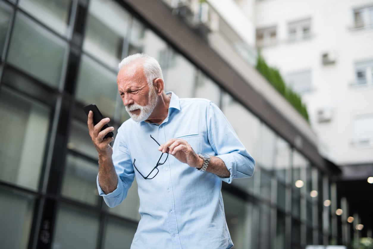 Senior man has bad eye sight. Making effort to see the screen.